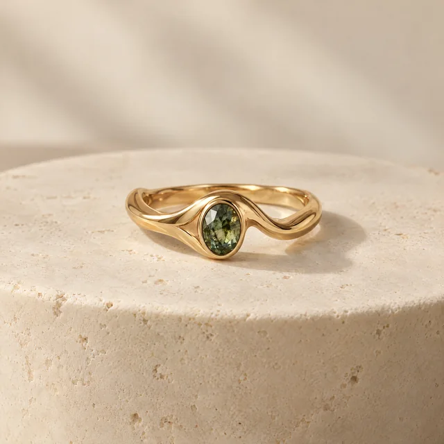 Gold ring concept with a green gemstone on an ivory pedestal